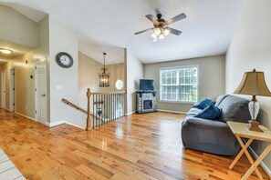 A spacious living room with hardwood flooring, a grey sofa, a fireplace, and a ceiling fan. - Pet-friendly Conover Home 7 Mi to Downtown Hickory (Conover)
