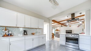 A modern kitchen with white cabinets, a patterned backsplash, and a blue tiled floor. - Countryside Texas Home w/ Fire Pit! (Richland Springs)