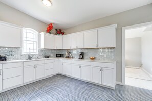A modern kitchen with white cabinets, a tiled backsplash, and a blue patterned floor.