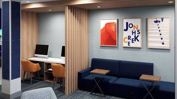 Een moderne kantoorruimte met een bureau, twee stoelen, een blauwe bank en drie ingelijste kunstwerken aan de muur.