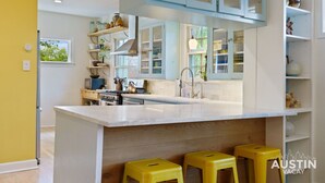 Una cocina moderna con una isla grande, taburetes amarillos y armarios azul claro.