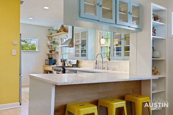 Una cocina moderna con una isla grande, taburetes amarillos y armarios azul claro.