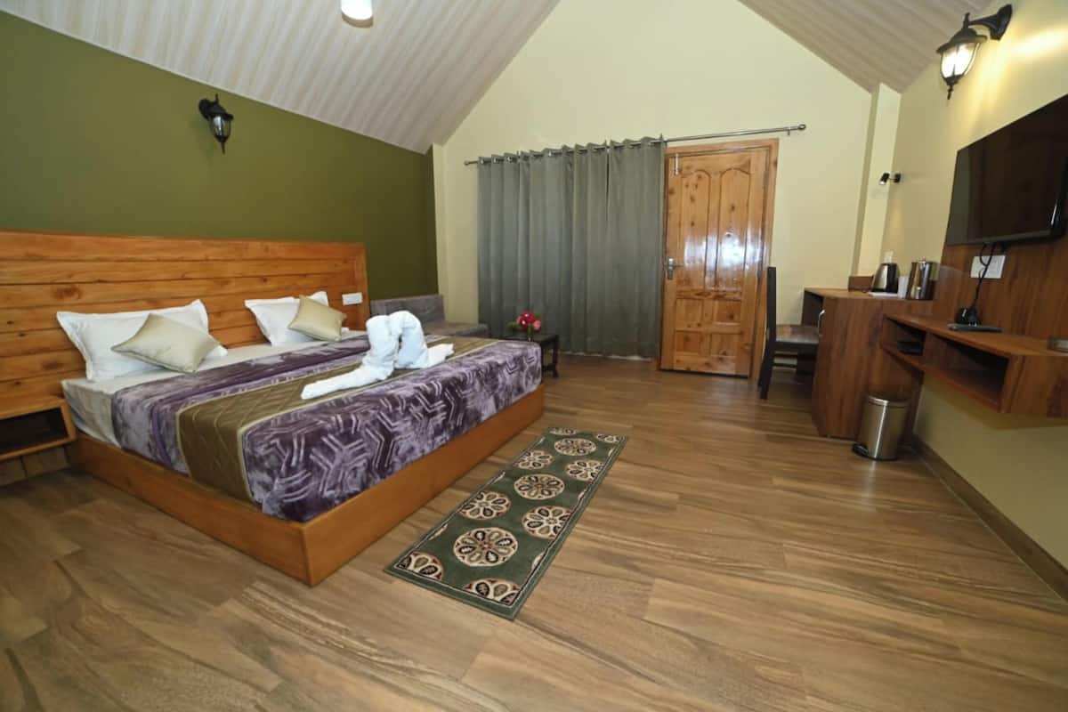 A bedroom with a wooden bed, a small desk, a television, and a door.