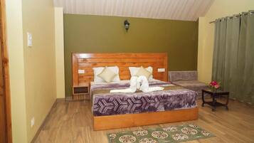 Une chambre à coucher avec un lit en bois, une table de chevet, une petite table sur laquelle est posé un vase, et un tapis à motifs.