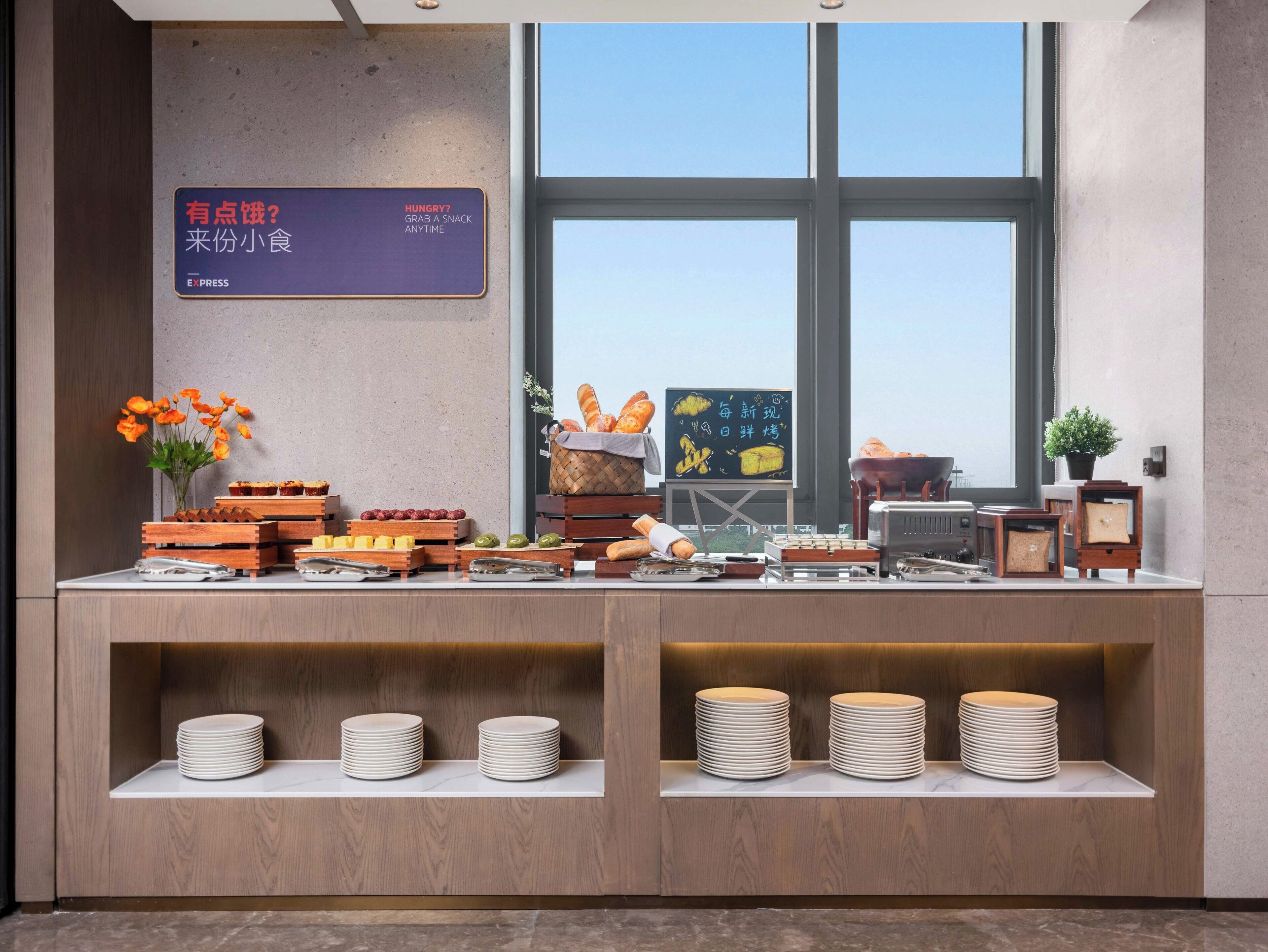 A buffet setup with various food items and a signboard in a modern interior.