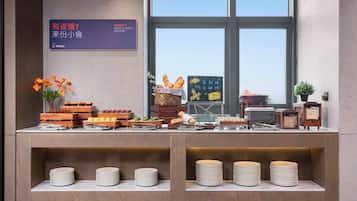 A buffet setup with various food items and a signboard in a modern interior.