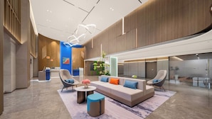 Un hall d’entrée moderne avec un canapé, des fauteuils, une table basse et un comptoir d’accueil.