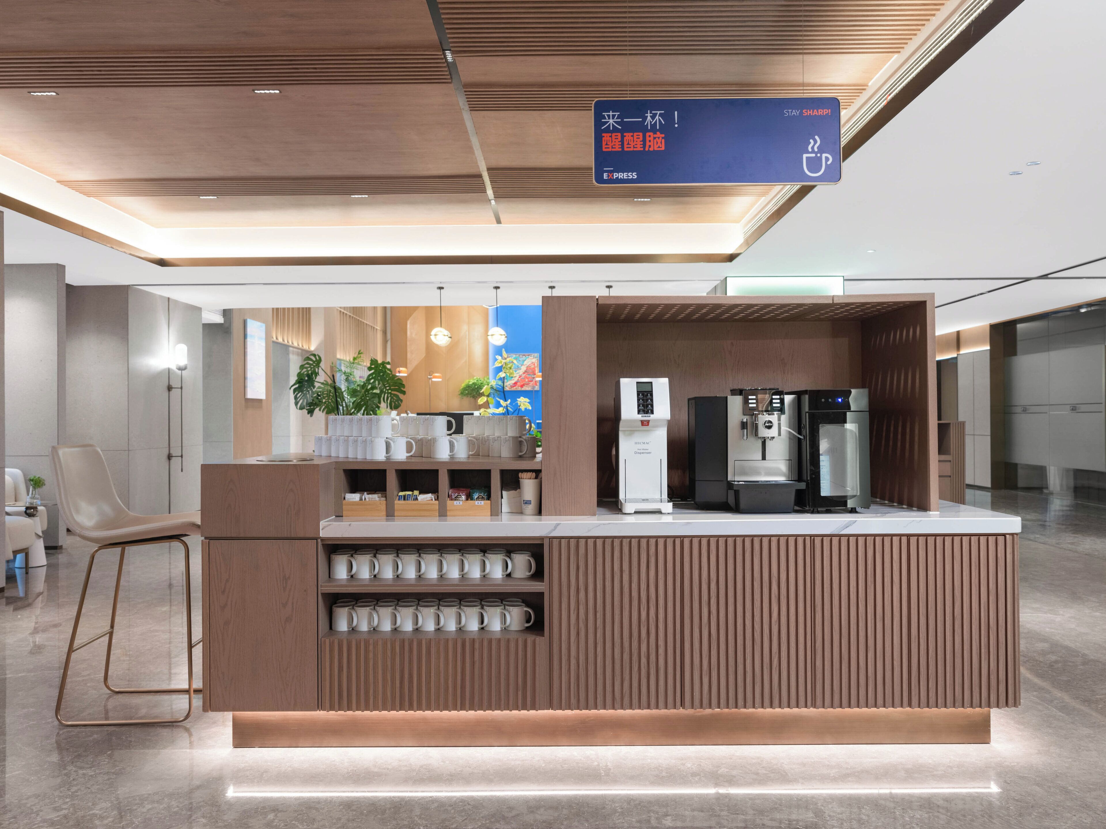 A modern coffee station with a coffee machine, a water dispenser, and a sign in a foreign language.