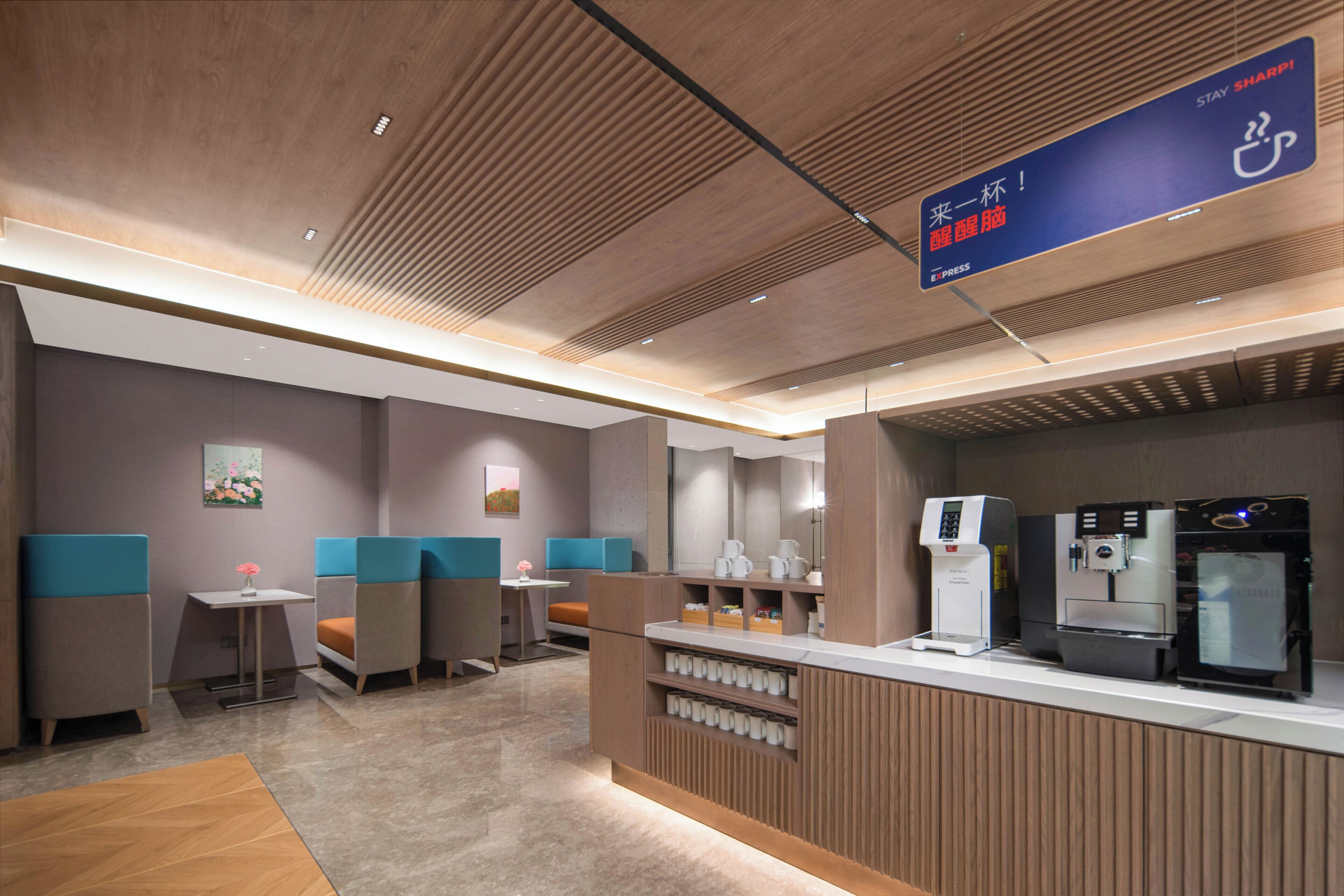 A modern hotel lobby with seating areas, a reception desk, and a coffee machine.