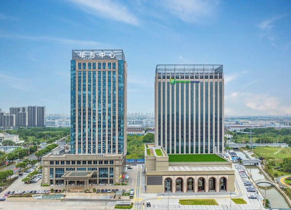 Two buildings stand alongside a river in an urban setting, offering a convenient parking area and a green space.