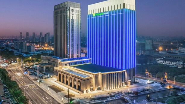 Un bâtiment moderne doté d’un élément lumineux vertical bleu très visible et d’une structure adjacente plus petite.