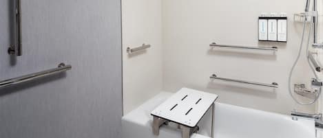 A modern bathroom with a walk-in shower, grab bars, a white bathtub, and a shelf with toiletries.