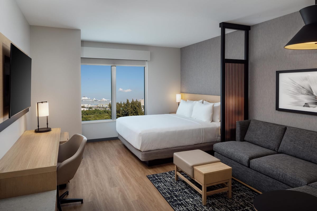 Ein modernes Hotelzimmer mit einem großen Bett, einem Schreibtisch, einer Couch und einem Fernseher.