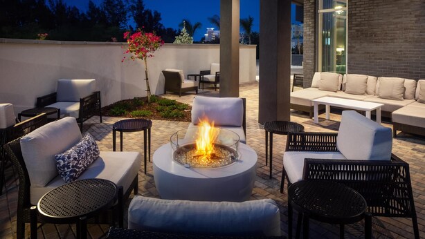 An outdoor patio area with a fire pit, seating, and a view of the city skyline at dusk. - Hyatt Place Cape Canaveral (Cape Canaveral)
