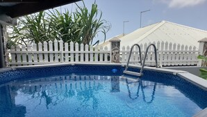 A swimming pool with a white picket fence and a tiled deck. - Villabadlou Ti-Cocon (Goyave)