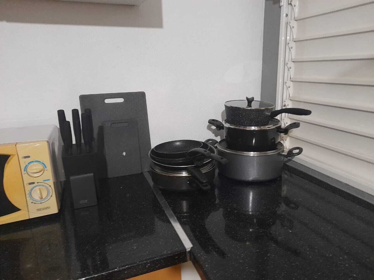 Una encimera de cocina con microondas, tostadora, cafetera y una olla sobre la hornilla.