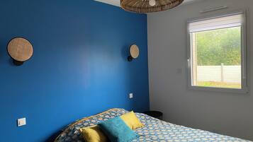 Ein Schlafzimmer mit Bett, Fenster und Wand mit einer runden Dekoration.