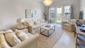 A spacious living room with a neutral color palette, featuring a sofa set, a coffee table, and a dining area.