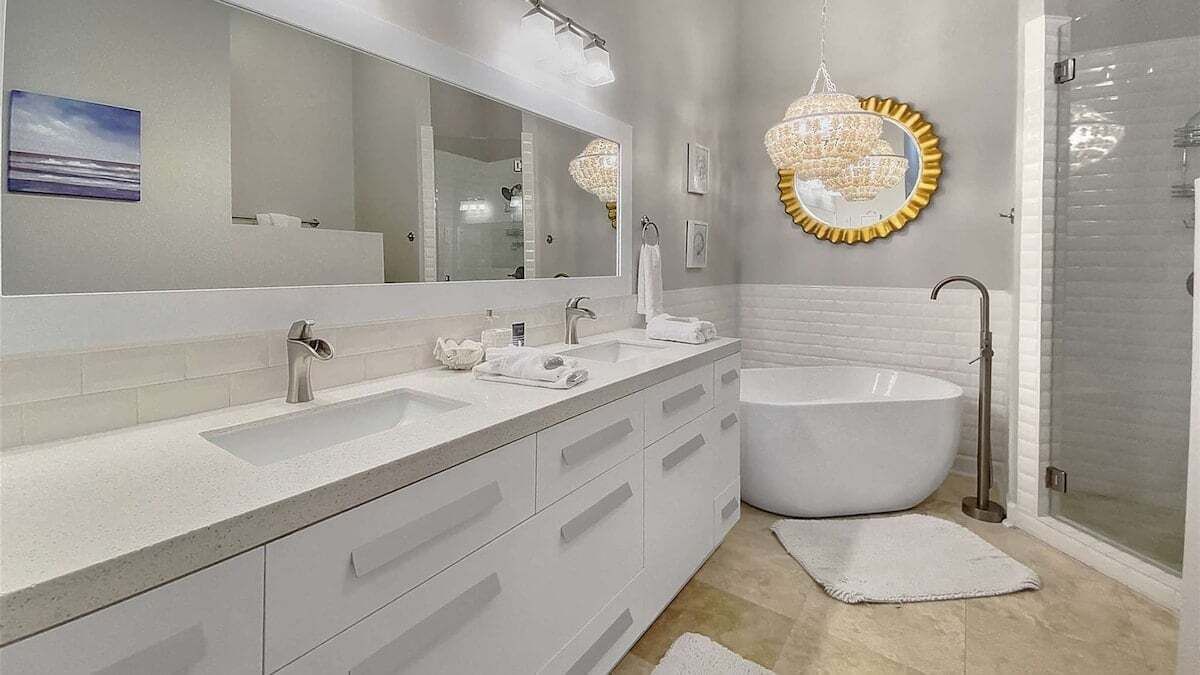 Un baño moderno con un espejo grande, dos lavamanos, una bañera y una ducha.