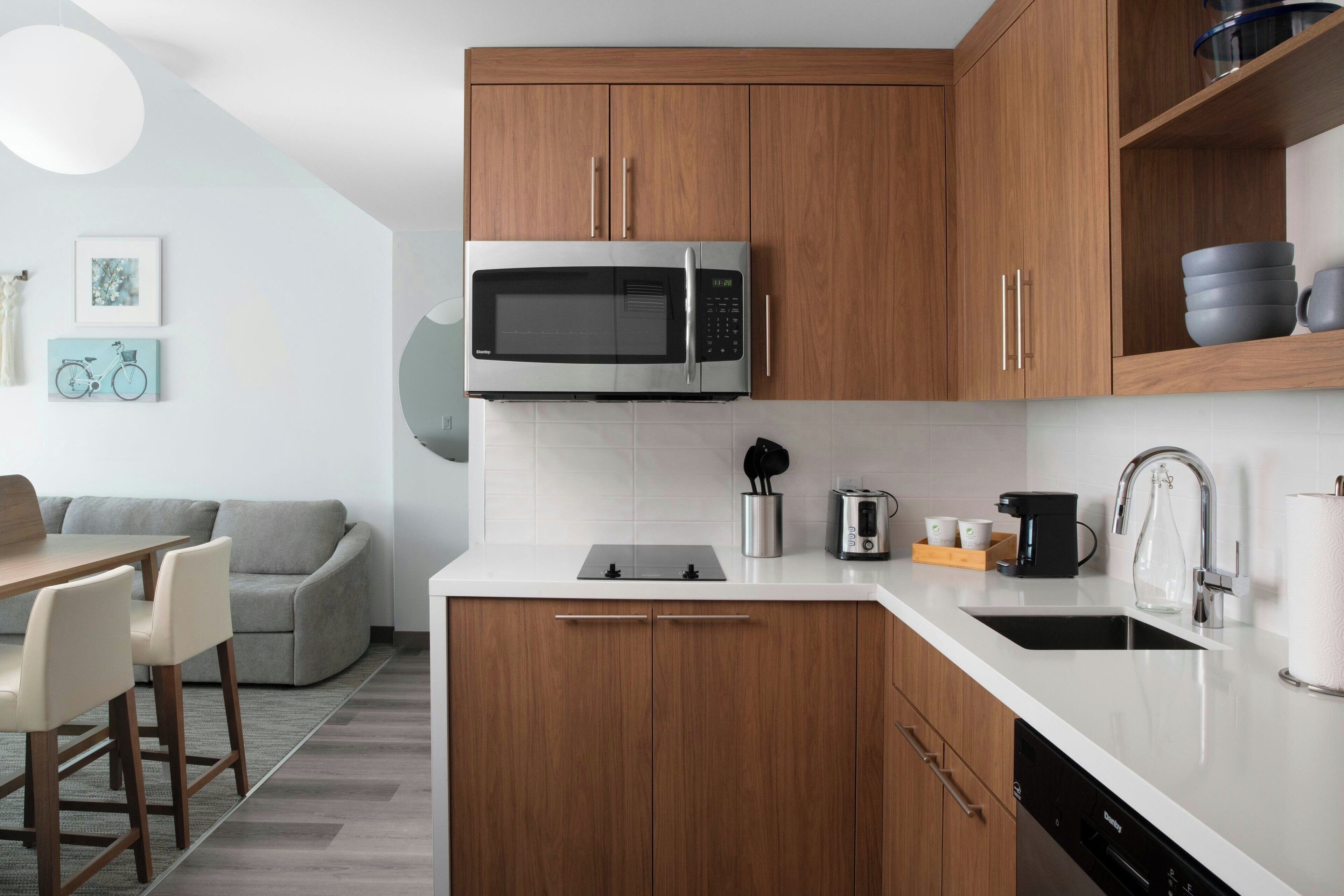 A modern kitchen with wooden cabinets, a built-in microwave, a coffee maker, and a dishwasher.