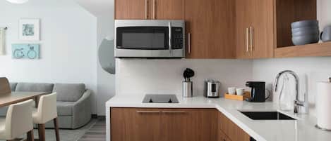 A modern kitchen with wooden cabinets, a built-in microwave, a coffee maker, and a dishwasher.