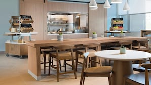 A modern kitchen with a central island, wooden cabinets, and pendant lighting. - Element by Marriott Fort Smith (Fort Smith)