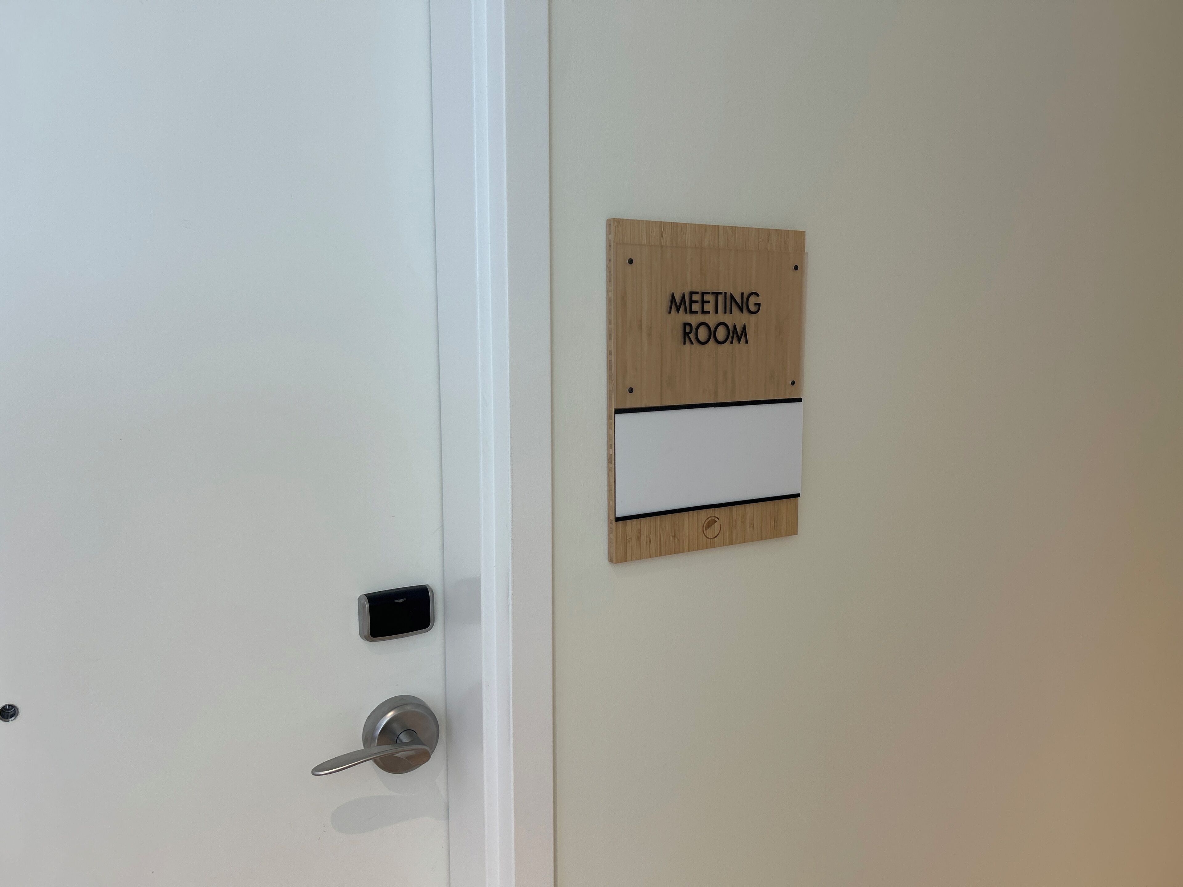 A door with a "MEETING ROOM" sign, a keycard reader, and a door handle.