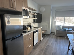 A modern kitchen with a built-in refrigerator, wooden cabinets, and a countertop with various appliances. - Element by Marriott Fort Smith (Fort Smith)