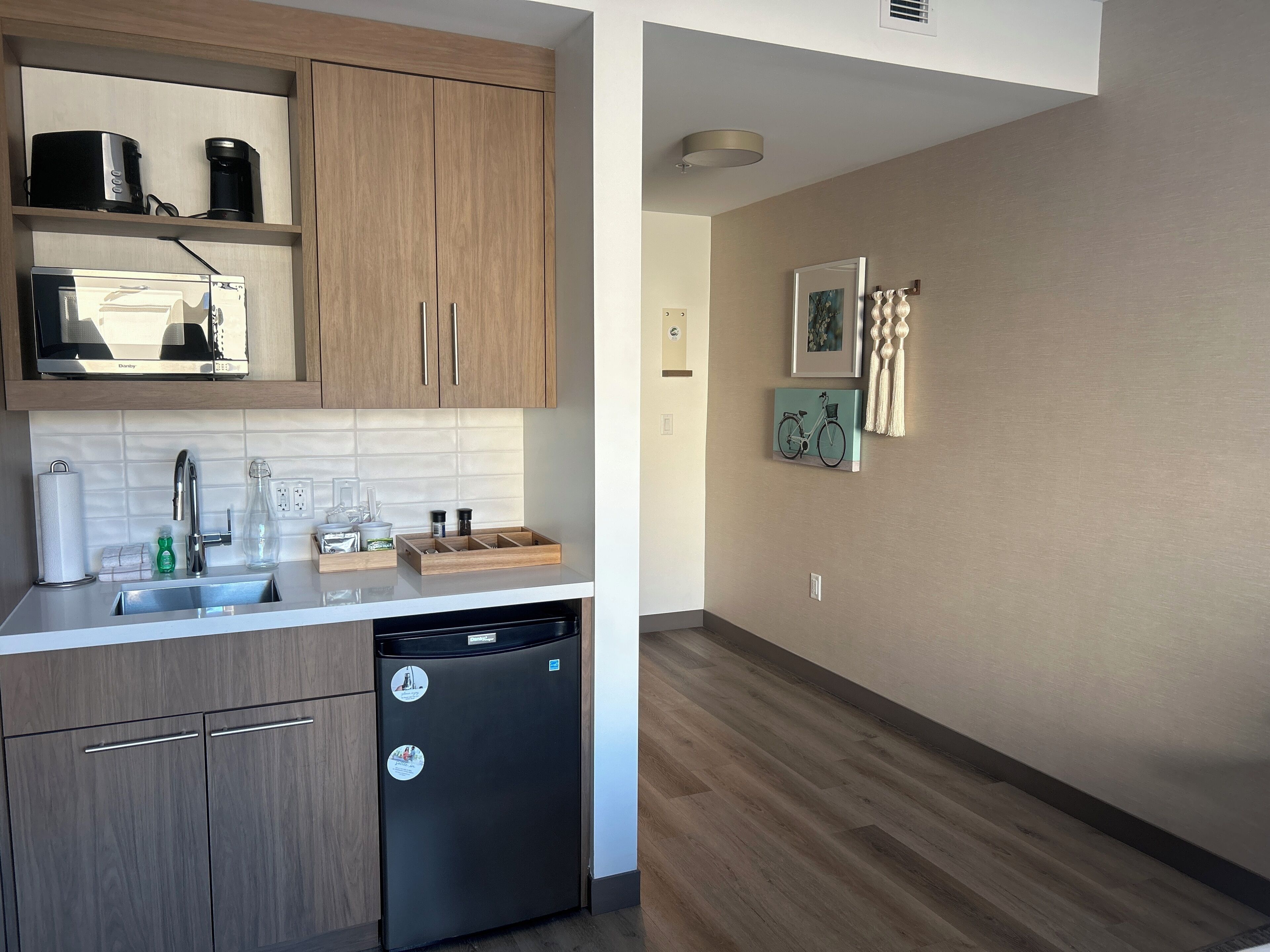 Una cocina moderna con armarios de madera, lavavajillas y una encimera con cafetera y microondas.