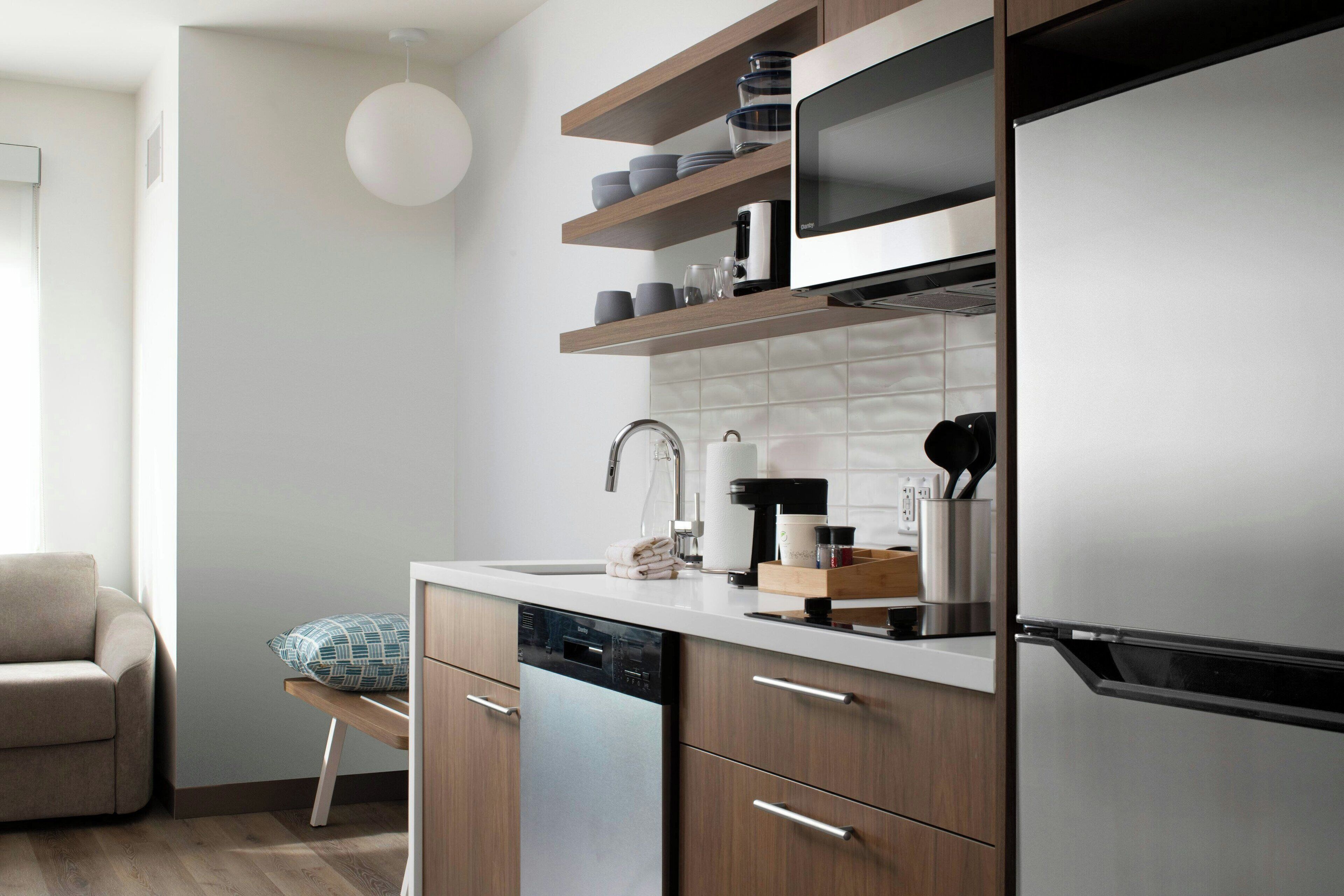 A modern kitchen with a dishwasher, a coffee maker, and a microwave on the countertop.