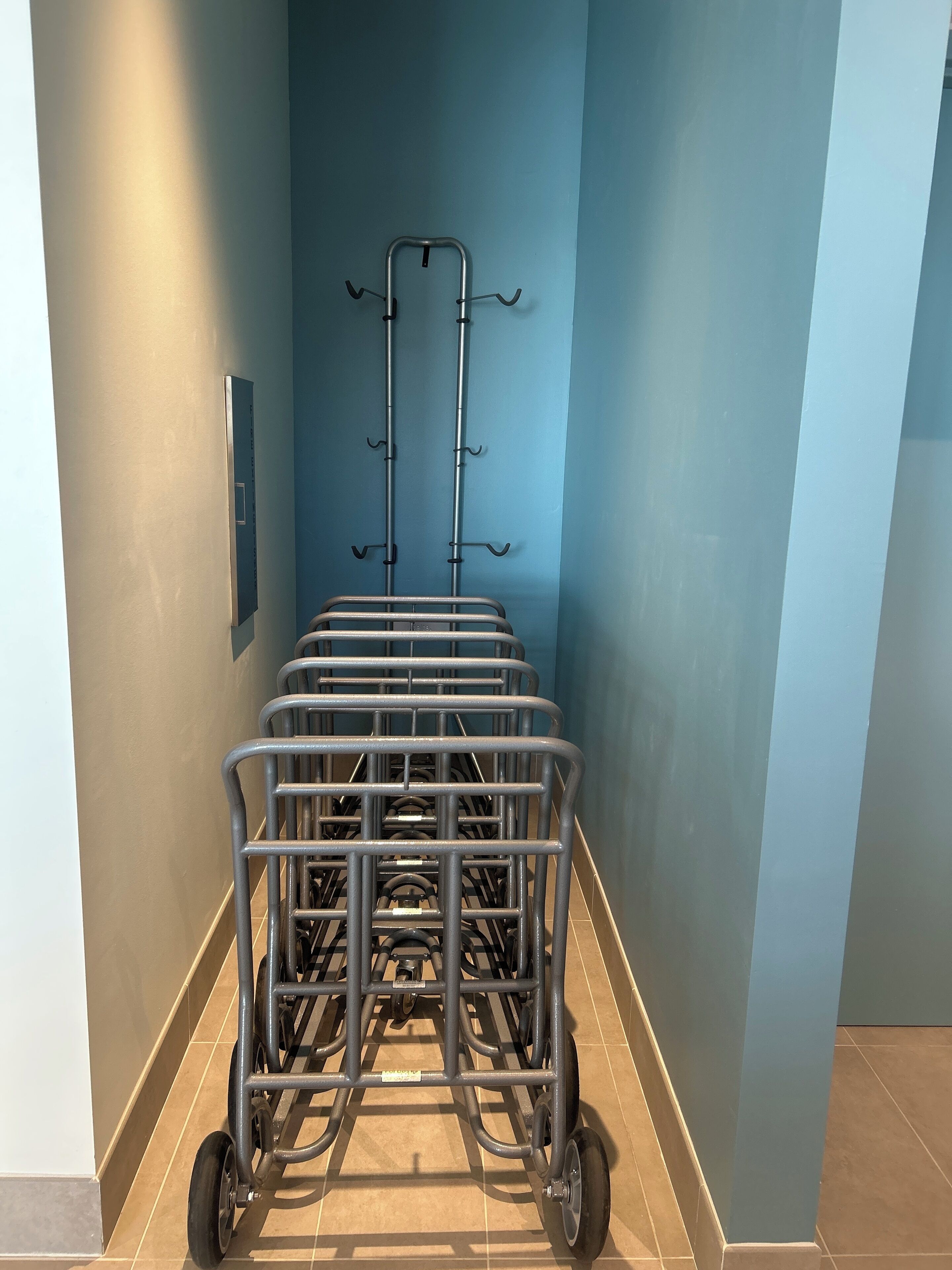 A narrow hallway with a metal cart and hooks on the wall.