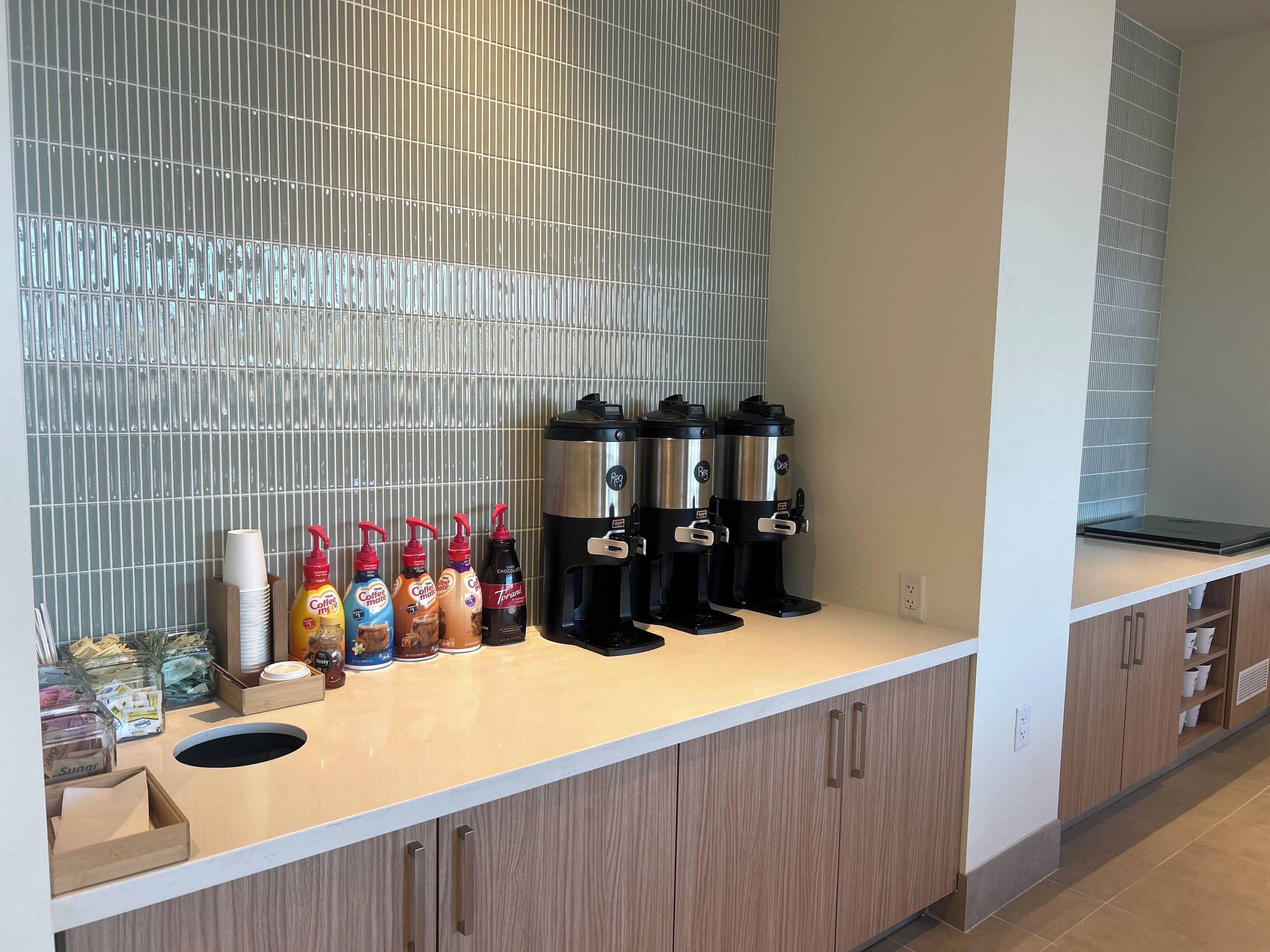Una estación de café con varios dispensadores y una variedad de opciones de café y té.