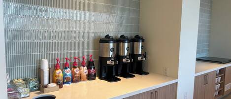 A coffee station with multiple dispensers and a variety of coffee and tea options.