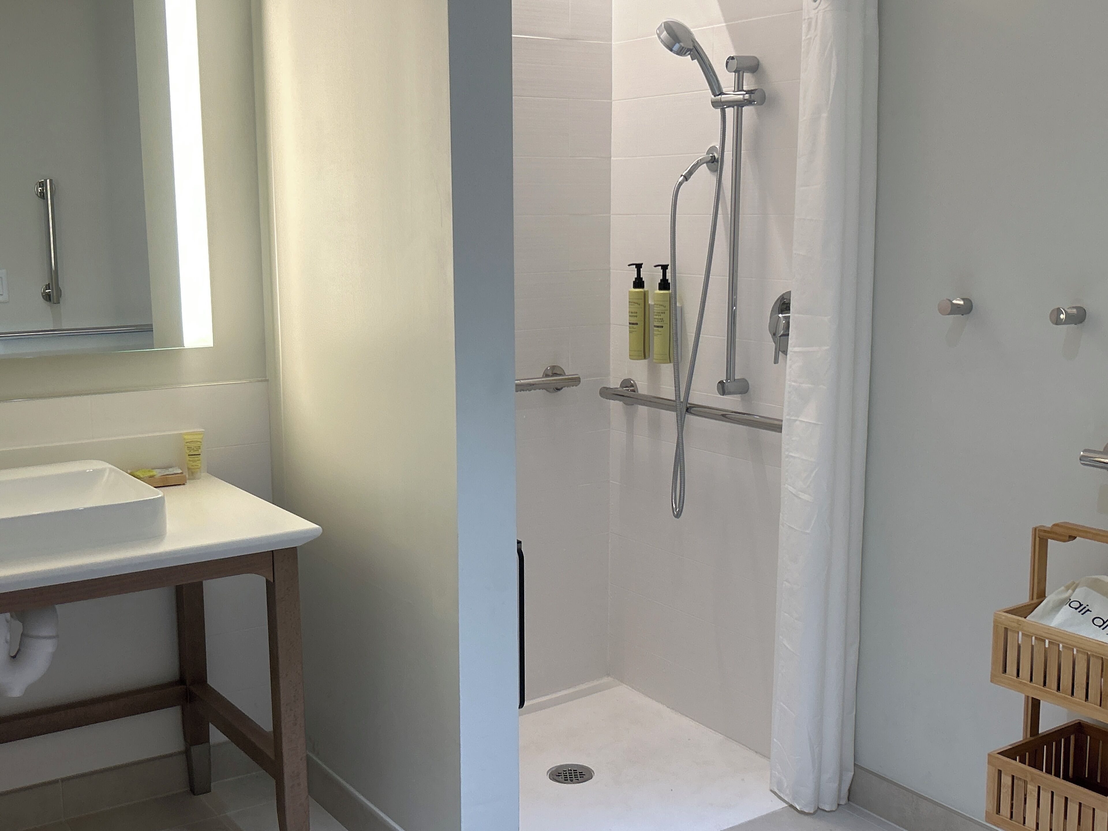 Un baño con lavamanos blanco, espejo y zona de ducha con cortina.
