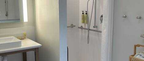 Un baño con lavamanos blanco, espejo y zona de ducha con cortina.