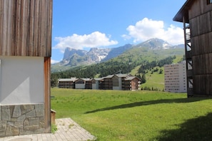Un hotel con varias construcciones, un muro de piedra y un campo cubierto de césped, con montañas al fondo.