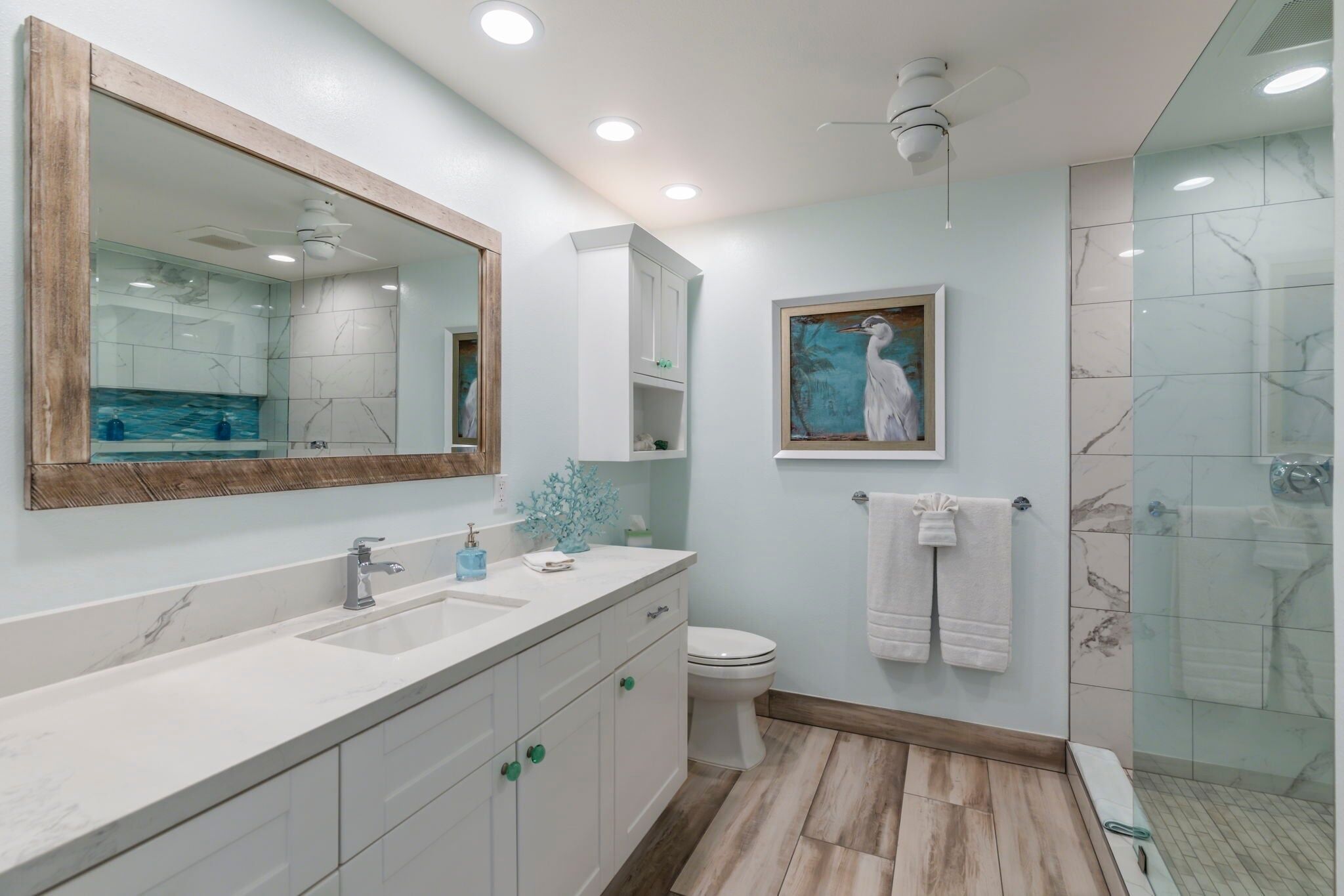A bathroom with a large mirror, a sink, a toilet, and a shower area.