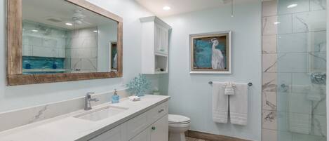 A bathroom with a large mirror, a sink, a toilet, and a shower area.