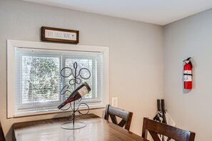 Enjoy meals in this dining area with a table and chairs, wine bottle, and window with blinds.