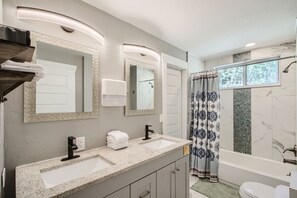 Features a dual sink vanity, large mirror, and soap dispenser.