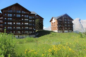 Ein Chalet-Hotel aus Holz mit mehreren Balkonen, gelegen an einem Hang mit Blick auf die Berge.