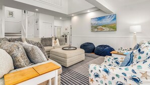 Ein geräumiges Wohnzimmer mit hoher Decke, einer Treppe und einem an einen Strand erinnernden Bett.