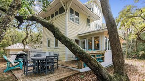 Ein zweistöckiges Haus mit Terrasse, umgeben von Bäumen.