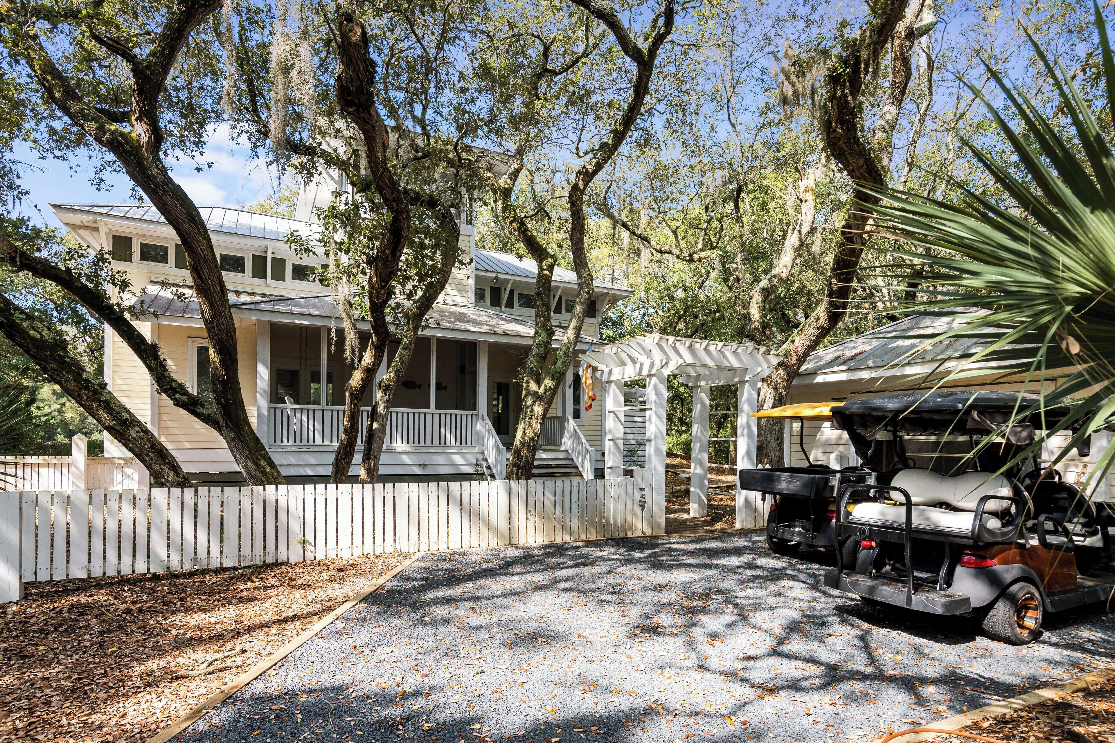 A two-story house with a porch, a covered patio, and a golf cart parked in front.