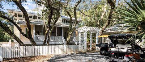 A two-story house with a porch, a covered patio, and a golf cart parked in front.