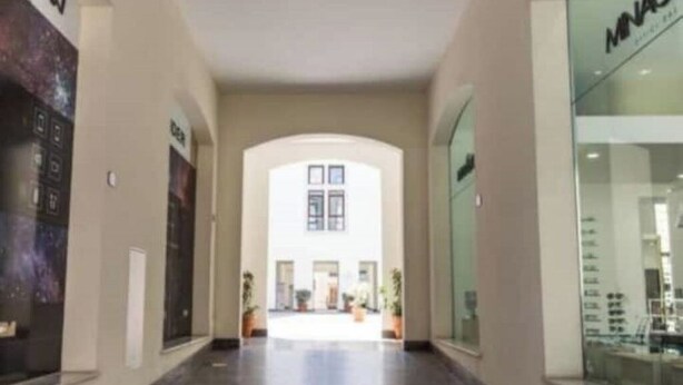 A corridor with a glass storefront on the right and a poster on the left. - shell Maqueda, bright and quiet apartment in the heart of the city (Palermo)