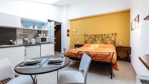 A compact room with a bed, a dining table with chairs, a kitchenette, and a small bedside table. - shell Maqueda, bright and quiet apartment in the heart of the city (Palermo)