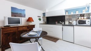 A compact kitchen with white cabinets, a microwave, a small refrigerator, and a dining area with a table and chairs. - shell Maqueda, bright and quiet apartment in the heart of the city (Palermo)