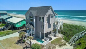A two-story house with a balcony and a small pool, located near a beach with a clear view of the ocean. - Aqua Vista | Oceanfront 5BR w/ Private Pool, Hot Tub & Stunning Views (Emerald Isle)