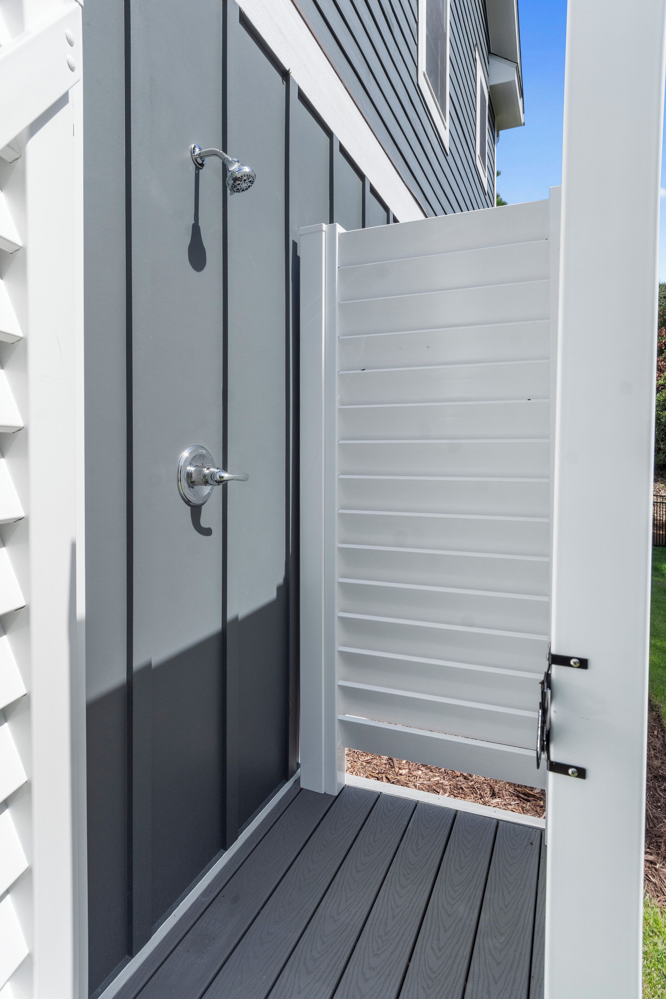 A white outdoor storage shed with a sliding door and a metal handle.
